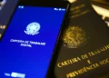 Smartphone exibindo a Carteira de Trabalho Digital ao lado de uma Carteira de Trabalho e Previdência Social física.