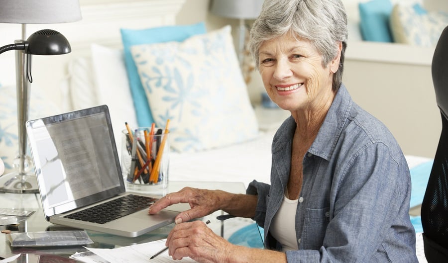Mulher madura trabalhando em casa no computador, representando reinício de profissão após os 50 anos.
