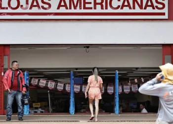 Entrada da Lojas Americanas com pessoas à frente e banners promocionais no interior da loja
