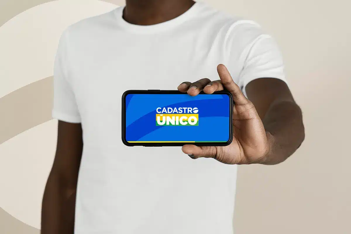  Pessoa segurando celular com a tela exibindo o logo do Cadastro Único em azul, branco, amarelo e verde