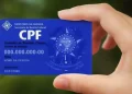 Close na mão segurando o cartão CPF azul da Secretaria da Receita Federal do Brasil