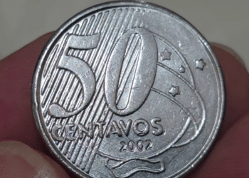 Close-up ampliado da moeda de 50 centavos do ano de 2002, em foco nos números e na palavra "CENTAVOS". A imagem destaca a busca por erros raros de cunhagem que podem elevar seu valor para colecionadores até R$ 400.