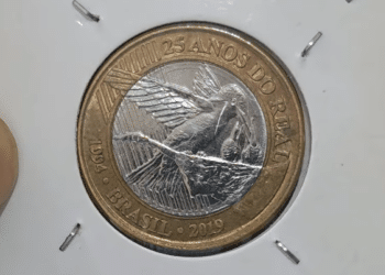 Cédula de 1 Real (antiga) e diversas moedas brasileiras espalhadas, simbolizando o valor encontrado e o potencial de lucro com a rara moeda comemorativa do Beija-Flor.