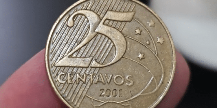 Close macro da face de uma moeda de 25 centavos de 2001, focando no numeral e no ano de fabricação, segurada por dedos em detalhe.