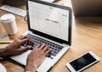 Pessoa escrevendo e-mail profissional em notebook, com foco na candidatura de emprego.