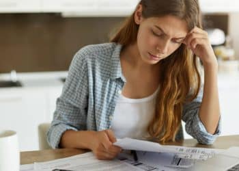 Mulher analisando boletos e contas em casa, preocupada com dívidas e possibilidades de negociação financeira.