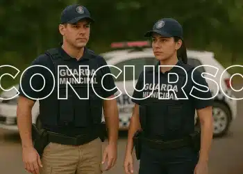 Dois guardas municipais uniformizados, um homem e uma mulher, em frente a uma viatura policial.