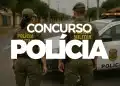 Dois policiais militares de costas em uma rua, ao lado de viatura oficial da polícia.