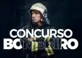 Bombeiro militar com uniforme de combate a incêndio e capacete, braços cruzados em fundo escuro com a frase "CONCURSO BOMBEIRO" em letras brancas.