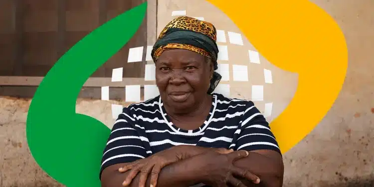 Mulher negra de meia idade usando lenço estampado, camiseta listrada e cruzando os braços em frente a parede