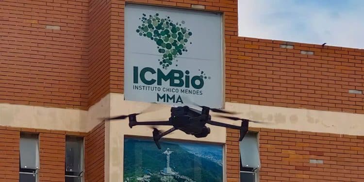 Drone preto voando próximo à fachada de tijolos do prédio do ICMBio com seu logotipo visível