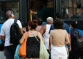Pessoas de diferentes idades esperando e entrando em ônibus público em ambiente urbano