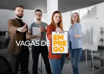 Grupo de profissionais em escritório exibindo um cartaz de “Emprego” e sinal de positivo, representando oportunidades de trabalho.