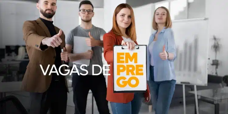 Quatro jovens em ambiente de escritório mostrando sinal de positivo e indicando placa com texto "Vagas de Emprego".