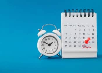 Calendário de mesa com despertador e pino vermelho marcando um feriado prolongado, simbolizando as oportunidades de "feriadões" em 2026 no Brasil.