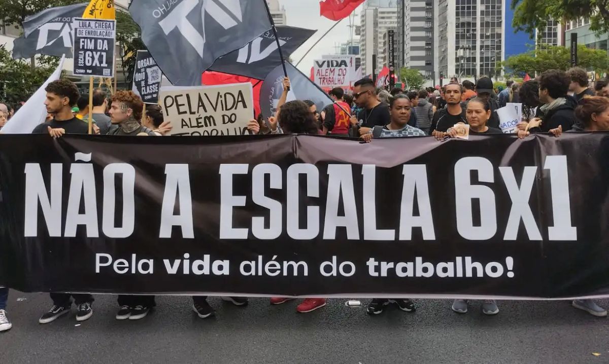 Manifestantes em ato público com faixa preta exigindo "NÃO À ESCALA 6X1" e "Pela vida além do trabalho!", relacionado à jornada de 36 horas semanais.