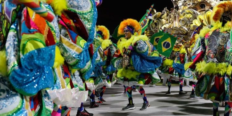 Foliões fantasiados desfilando no Carnaval brasileiro, representando a festa marcada para fevereiro de 2026.