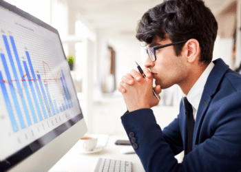 Profissional analisa gráficos de desempenho e dados estratégicos em ambiente corporativo de tecnologia.