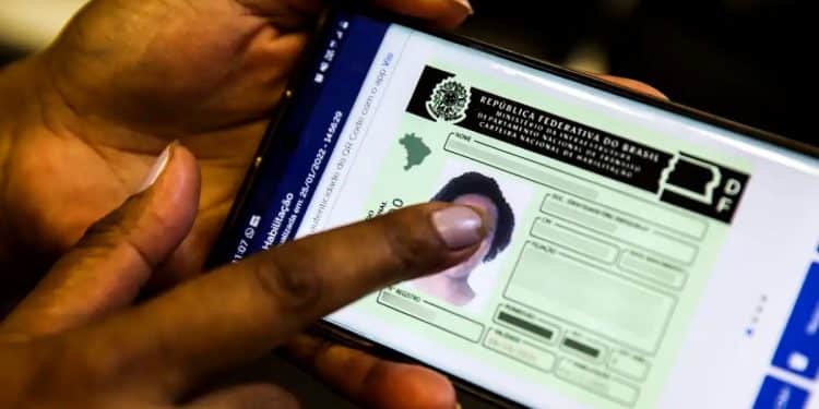Mãos segurando um celular com a CNH Digital exibida, ilustrando a medida do governo federal para desburocratizar e reduzir em até 80% o custo de obtenção da Carteira Nacional de Habilitação.