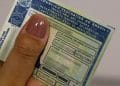 Pessoa segurando a Carteira Nacional de Habilitação (CNH) no formato tradicional. A imagem ilustra o documento que pode ter novas regras de emissão, permitindo a retirada sem a obrigatoriedade de autoescola.