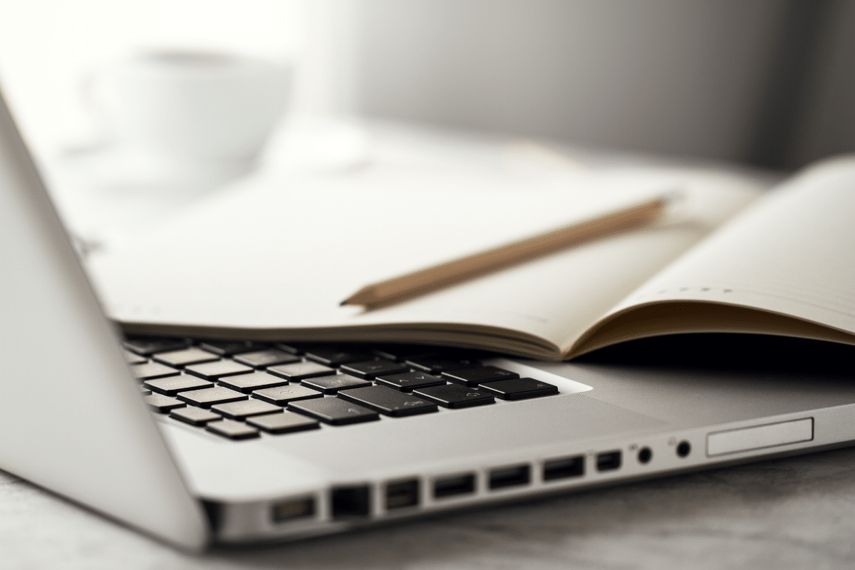 Notebook aberto com caderno e lápis sobre o teclado em mesa clara