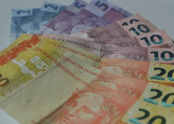 Dinheiro brasileiro em papel, com notas de 5, 10 e 20 reais em superfície branca