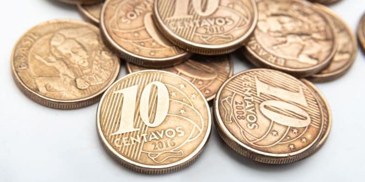 Close-up de moedas de 10 centavos do Real, incluindo o ano de 2008, destacando a raridade por defeitos de cunhagem. A imagem ilustra a busca por peças valiosas para colecionadores.
