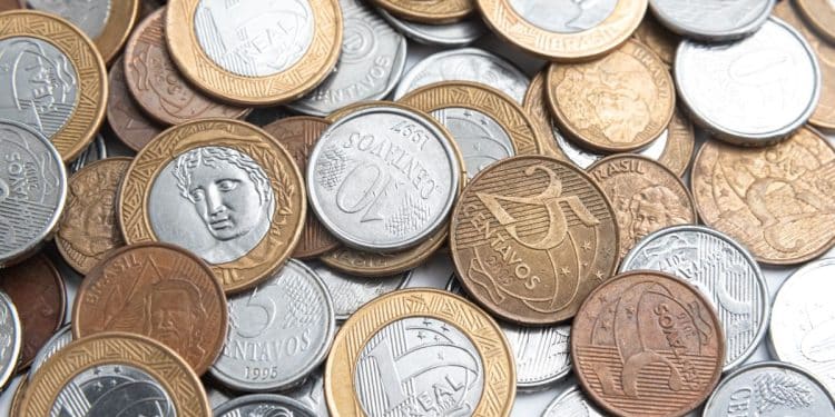 Close-up de diversas moedas antigas de diferentes países e épocas, incluindo peças de cobre e prata, dispostas sobre uma superfície de madeira rústica.