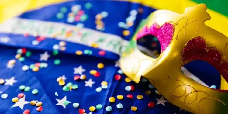 Máscara dourada decorada com detalhes em rosa e glitter sobre bandeira do Brasil decorada com confetes coloridos