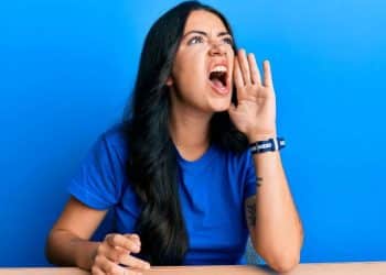 Mulher falando alto e gesticulando, representando o impacto da linguagem na comunicação e no comportamento.