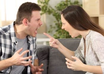 Casal discutindo intensamente no sofá durante um conflito.