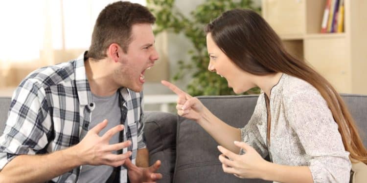 Casal discutindo intensamente no sofá durante um conflito.