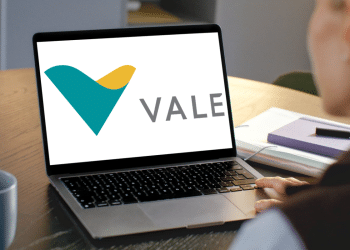 Pessoa olhando para o logo da Vale exibido em um notebook aberto sobre a mesa