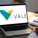 Pessoa olhando para o logo da Vale exibido em um notebook aberto sobre a mesa