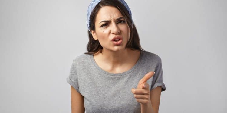 Mulher com expressão de brava apontando o dedo, ilustrando comportamentos de pessoas rudes e imaturas.