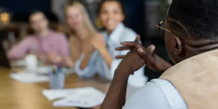 Grupo de pessoas em uma reunião de escritório, com um participante falando enquanto os outros escutam.