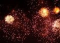 Fogos de artifício dourados brilhando e explodindo contra um céu escuro durante uma celebração noturna.