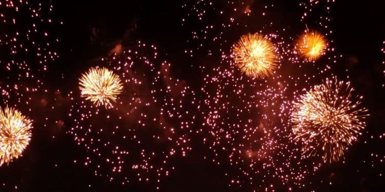 Fogos de artifício dourados brilhando e explodindo contra um céu escuro durante uma celebração noturna.