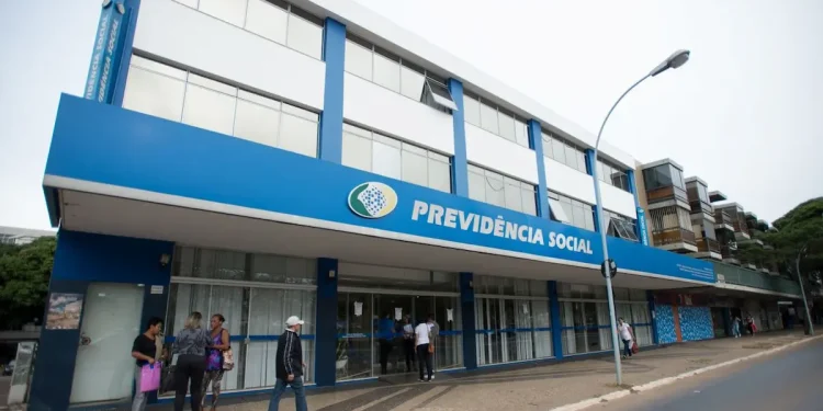 Fachada de uma agência da Previdência Social, com pessoas aguardando informações, representando a antecipação do 13º salário do INSS em 2026.