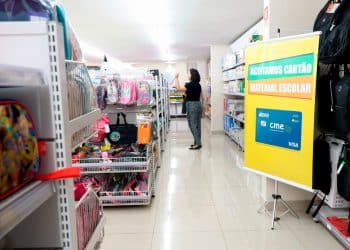 Loja de papelaria com banner indicando aceitação do Cartão Material Escolar do GDF com bandeira Visa.