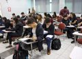 Fiscal acompanhando aplicação de prova em sala de aula com estudantes.