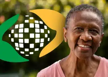 Mulher idosa sorrindo com pele negra, usando camiseta rosa, fundo desfocado com folhas verdes e logo estilizado verde e amarelo.