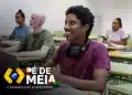 Estudante sorrindo em sala de aula com laptop e fones de ouvido, ilustrando o Pé-de-Meia Licenciaturas 2026.