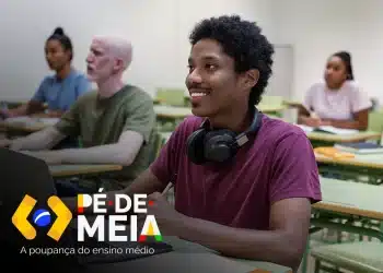 Estudante sorrindo em sala de aula com laptop e fones de ouvido, ilustrando o Pé-de-Meia Licenciaturas 2026.
