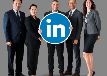 Grupo diversificado de cinco profissionais com roupas de negócios segurando logo do LinkedIn