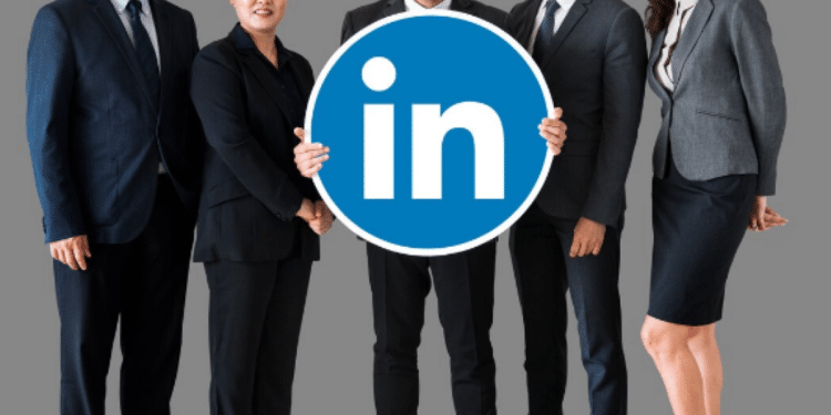 Grupo diversificado de cinco profissionais com roupas de negócios segurando logo do LinkedIn