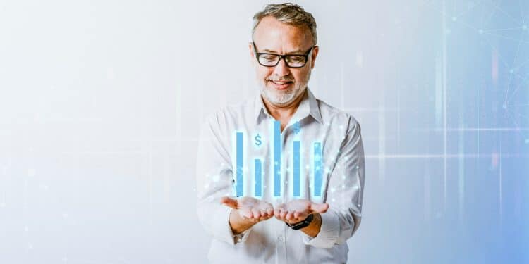 Homem sorridente com cabelos grisalhos e óculos segurando gráficos digitais de barras azuis com símbolos de dólar.
