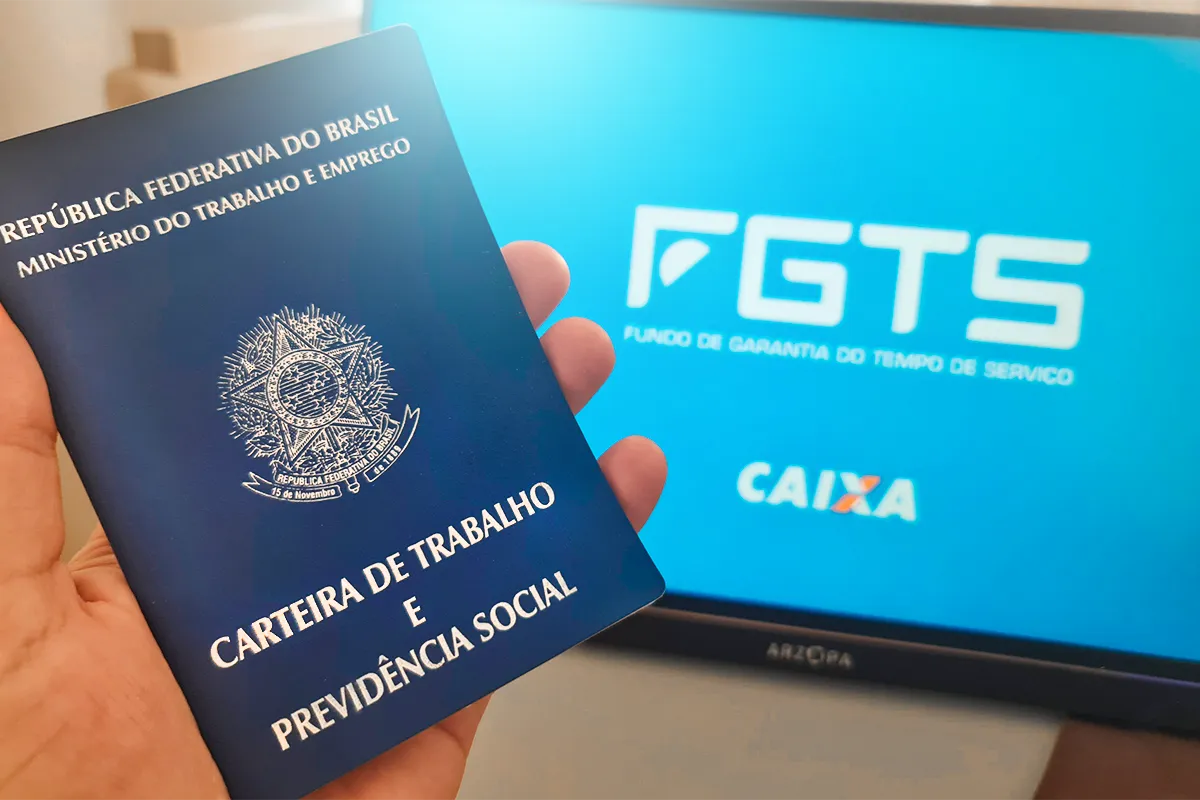 Carteira de Trabalho brasileira em mão com tela de FGTS ao fundo, direitos em 2026