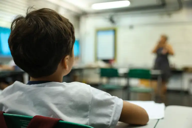 Mulher analisando produtos escolares em prateleira com fitas coloridas e réguas laranja à venda