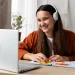 Mulher sorridente usando fones de ouvido, com laptop e post-its, simbolizando a aprendizagem e o desenvolvimento de habilidades com cursos online gratuitos.